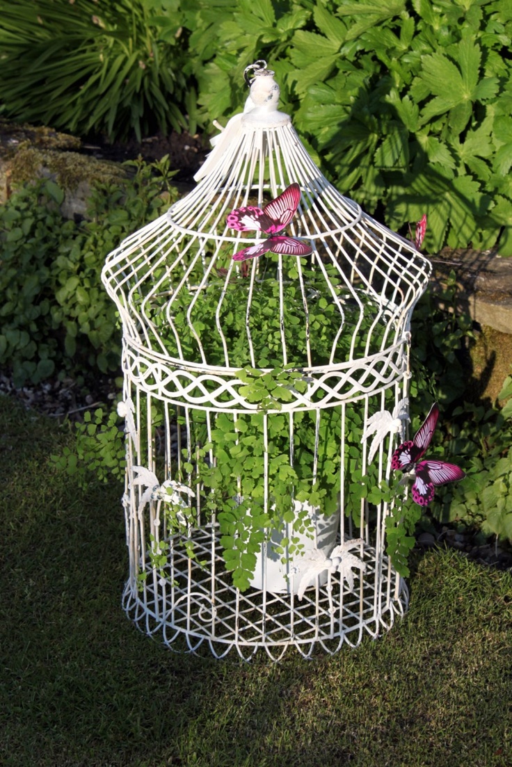 Bird cage with butterflies attached to the outside.