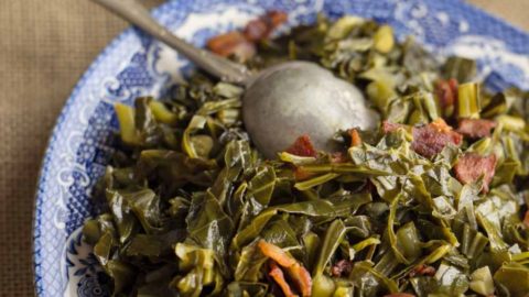Sautéed Brussels sprouts leaves with bacon in a serving dish with a spoon.