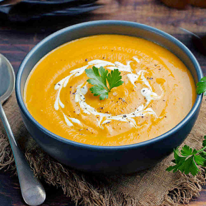 Curried carrot soup in a bowl with parsley.
