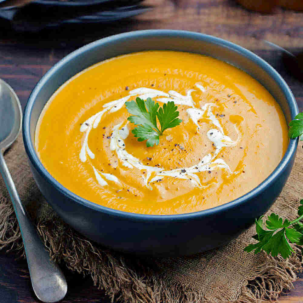 Curried carrot soup in a bowl with parsley.