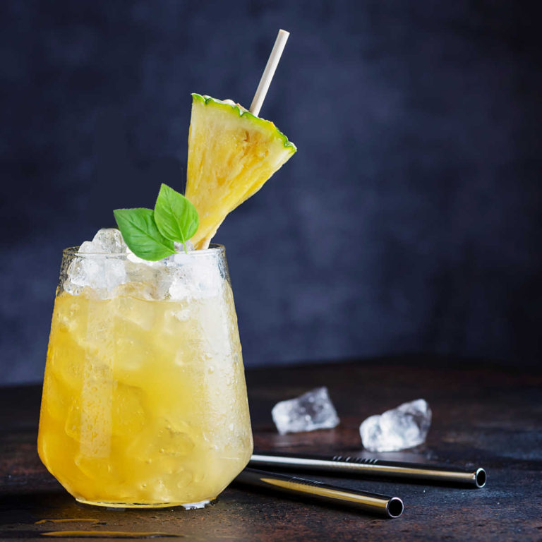 Pineapple and basil in a tequila drink with ice cubes.