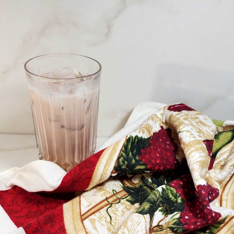 Black Russian made with chocolate milk and cream near a colorful tea towel.