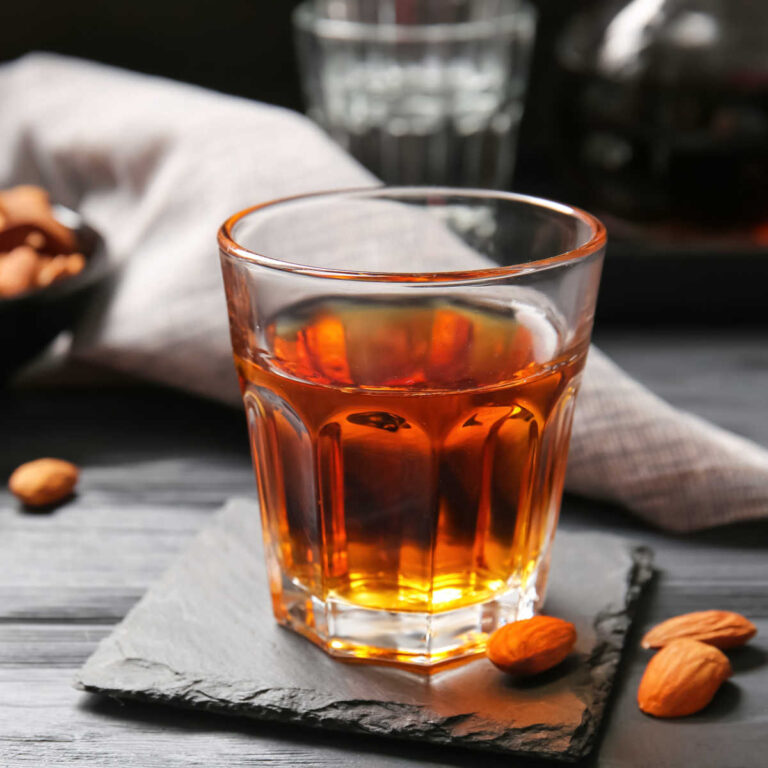 Glass of Amaretto with almonds and gray cloth on a slate counter.