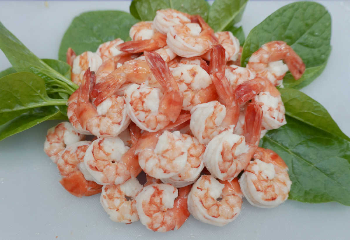 Cooked and cleaned shrimp with basil leaves.