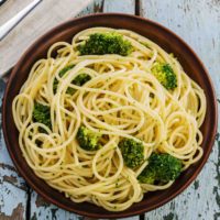 Broccoli and garlic with pasta in a brown bowl.