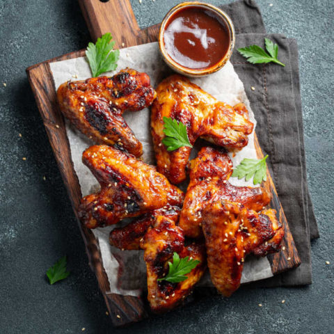 Sticky chicken wings with sauce on a cutting board