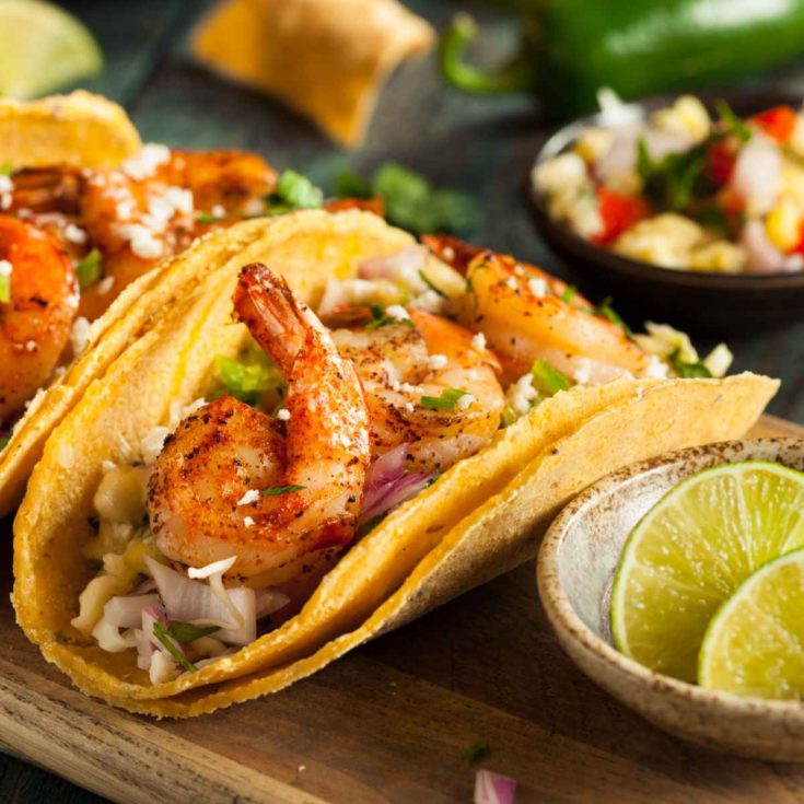 Spicy shrimp tacos with cabbage slaw and lime slices.