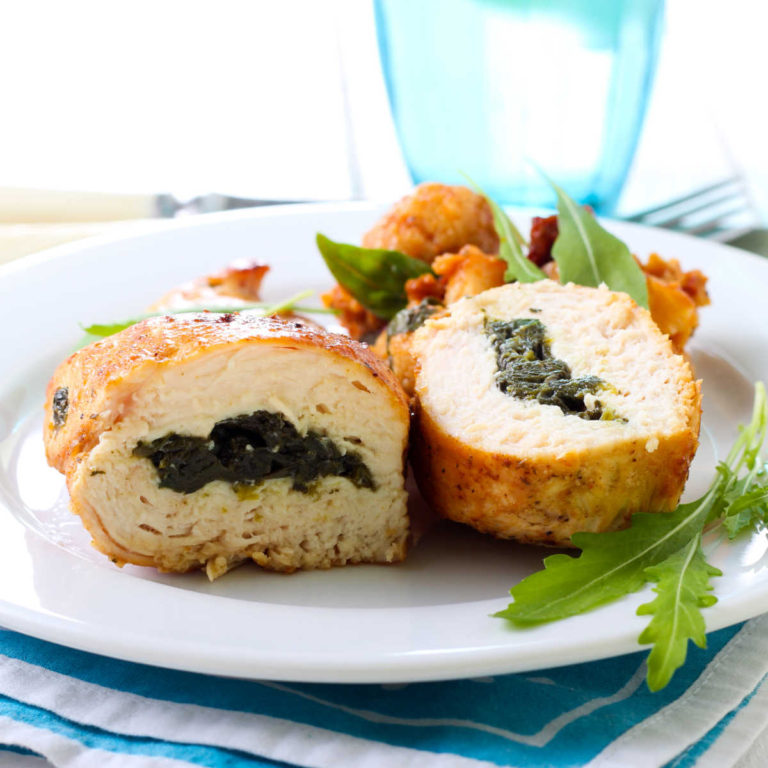 Stuffed chicken rolls on a white place with a blue napkin.