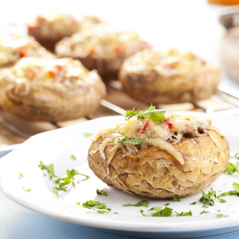 Stuffed portobello mushroom on a white plate with parsley.