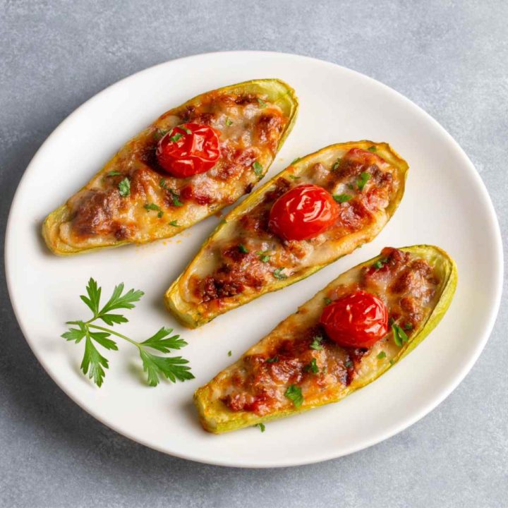 Yellow squash on a white plate stuffed with beef and cheese.