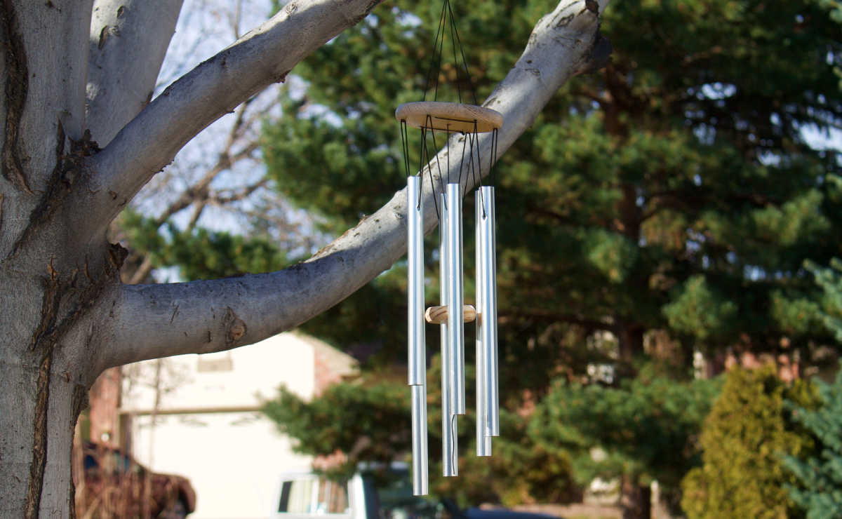 A metal wind chime hanging in a tree.