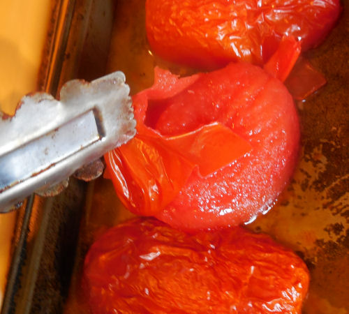 Use tongs to peel the skins from roasted tomatoes