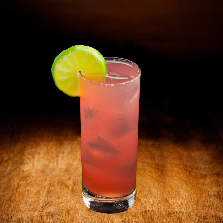 Floridora cocktail on a wood table with lime wheel..