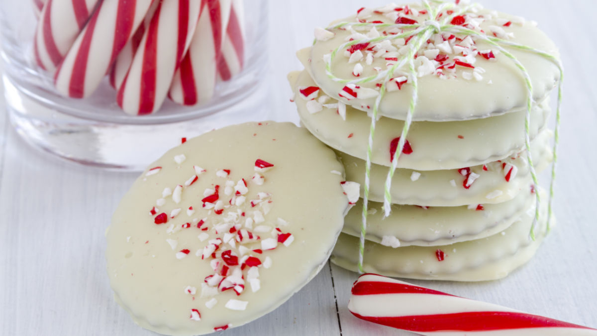 Peppermint crunch cookies tied with white twine next to a peppermint stick and jar of more peppermint sticks.
