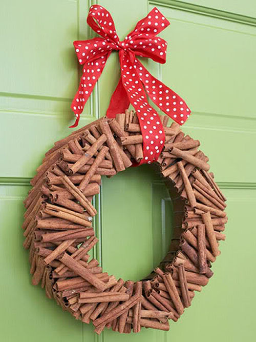 Cinnamon Stick Christmas wreath from bhg.com on a green door with a red and white ribbon.
