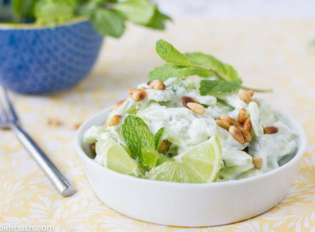 Cucumber salad with honey lime yogurt in a white bowl.