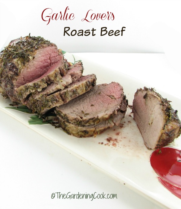 Roast beef with fresh herb crust on a white plate with words Garlic Lovers Roast Beef.