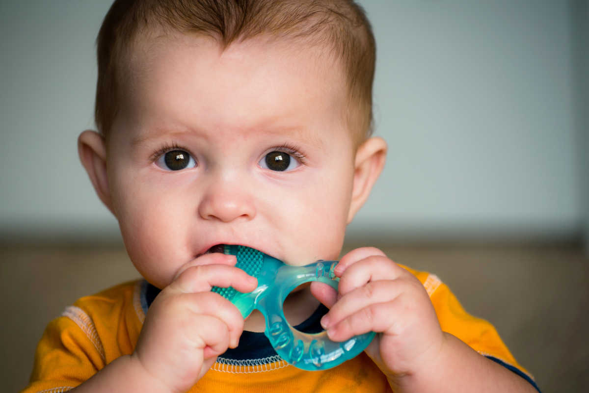 Baby teething on a plastic ring.