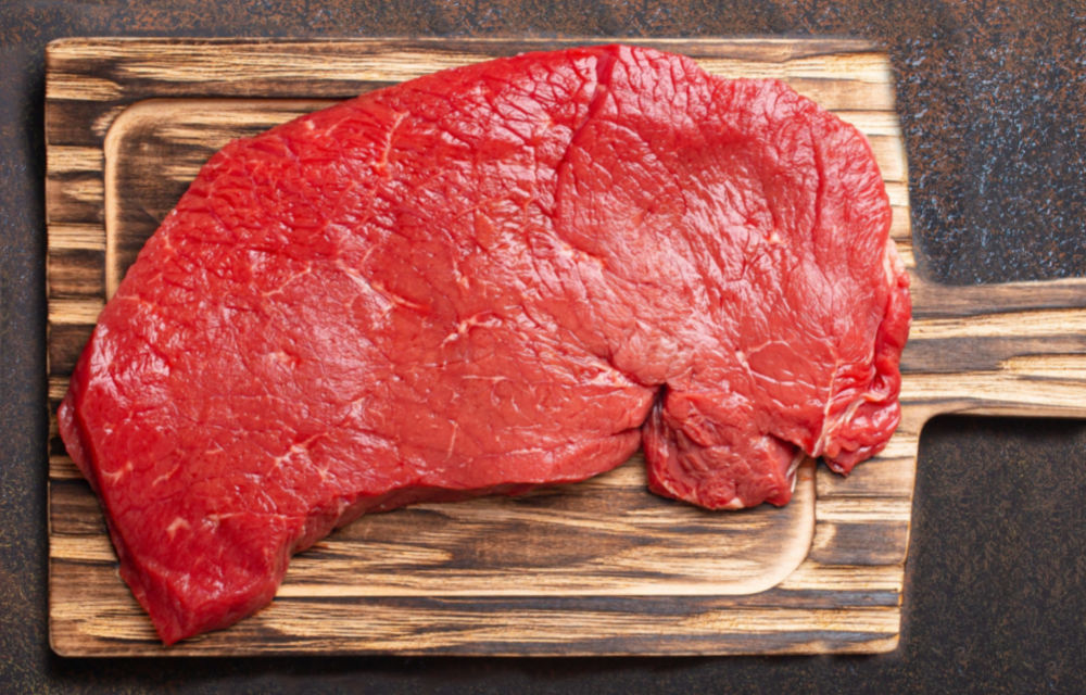 A cut of top round steak on a cutting board.