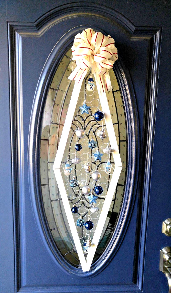Christmas ornament door decoration on a blue door with oval glass.