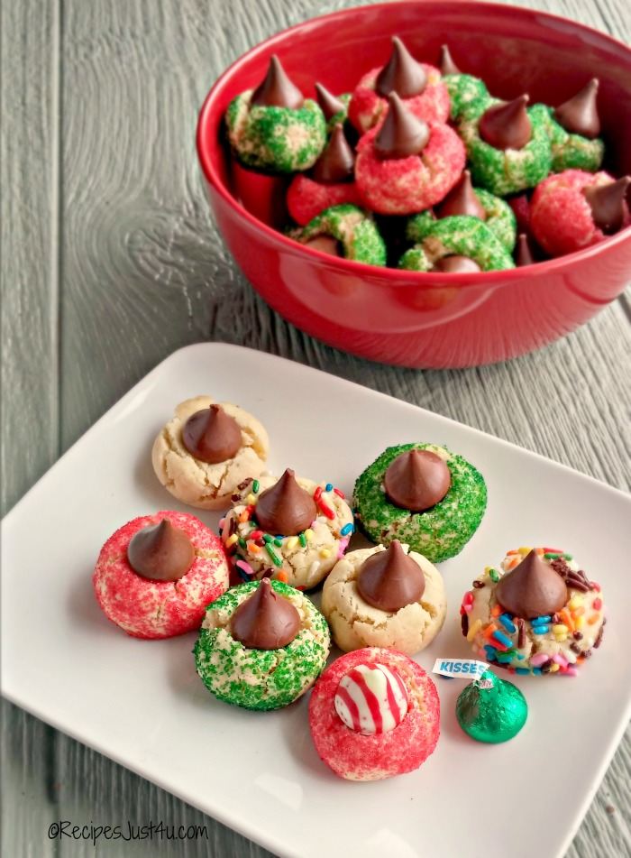 Christmas kiss cookies A plate of Christmas kiss cookies with red and green sprinkles, with a red bowl filled with more cookies in the background.