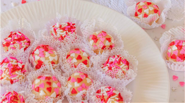 Brazilian white chocolate truffles on a white plate decorated with red and pink candy hearts.
