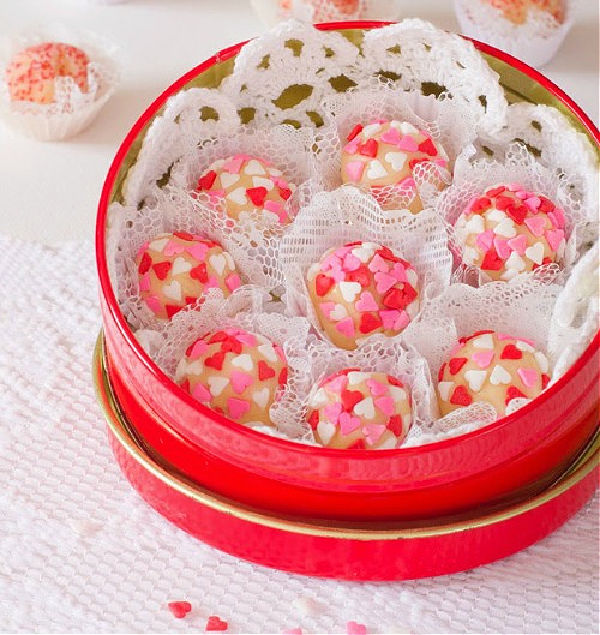 Brigadeiro recipe featuring truffles decorated with red and white hearts in a red tin for gifting.
