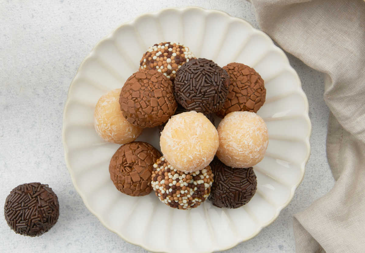 A white plate with brigadero truffles next to one truffle.