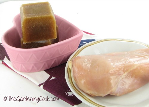 Frozen left over gravy made n silicone ice cube trays near some raw chicken.