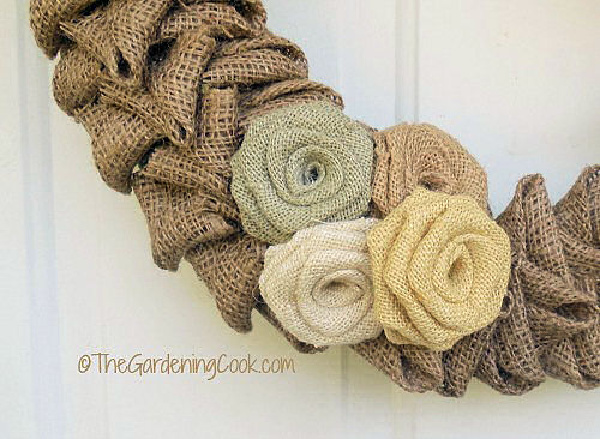 A cluster of four burlap roses on a burlap welcome wreath.
