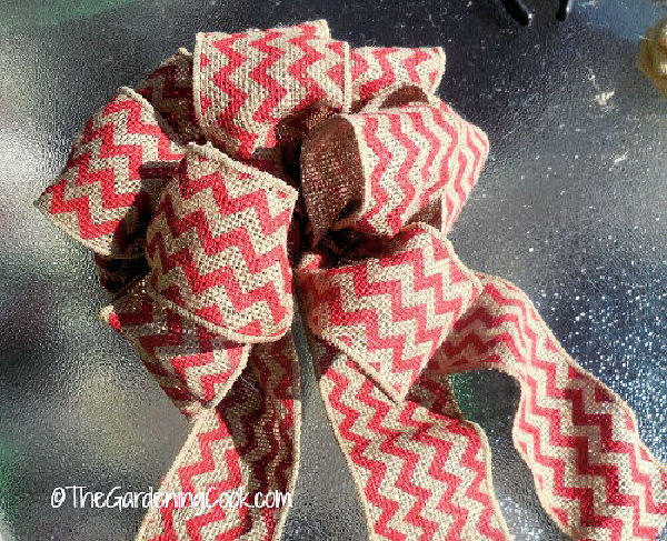 A large bow made from chevron striped orange and tan burlap.