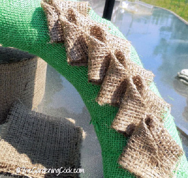 Brown burlap petals in the center of a green burlap wreath form.