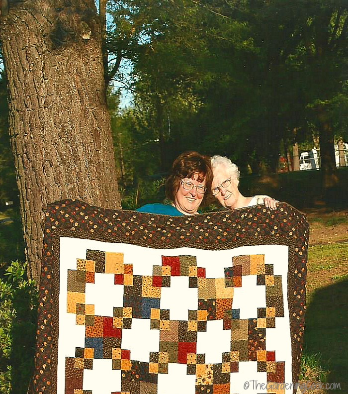 Two women holding a hand made quilt.
