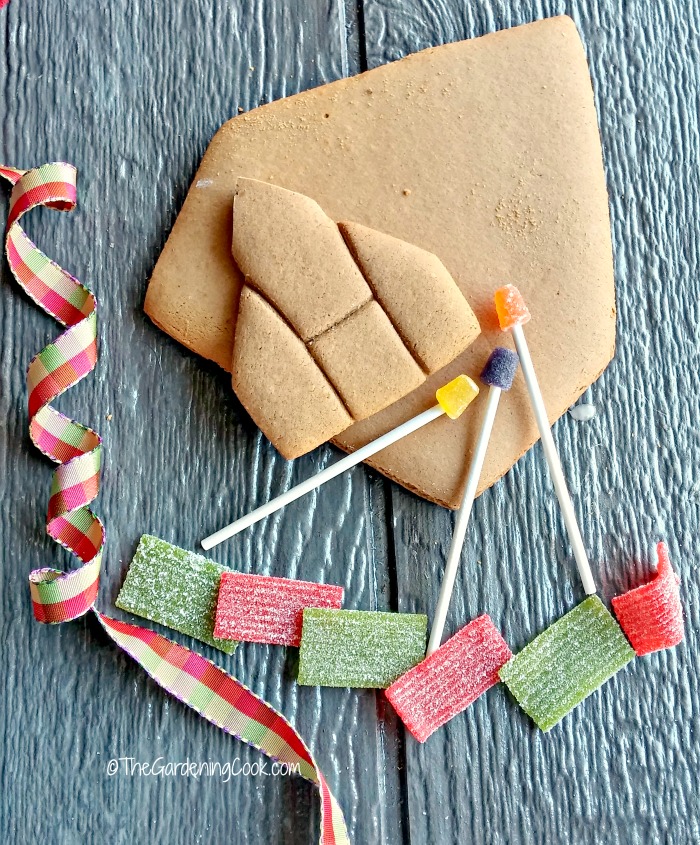 Ribbon, candy, gingerbread pieces and gum drop street lights on a wooden board.