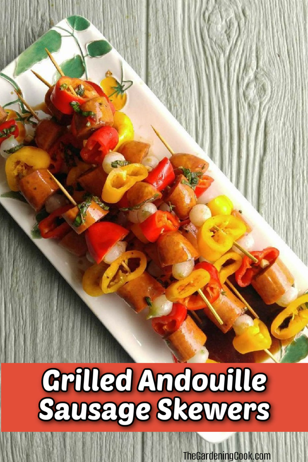Grilled Andouille sausage skewers on a flowered plate with vegetables.