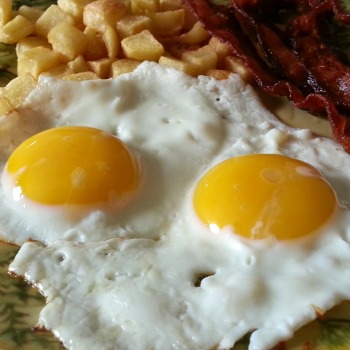 Eggs sunny side up with hash brown potatoes.