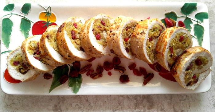 Cranberry stuffed pork tenderloin on a colorful platter arranged in slices.
