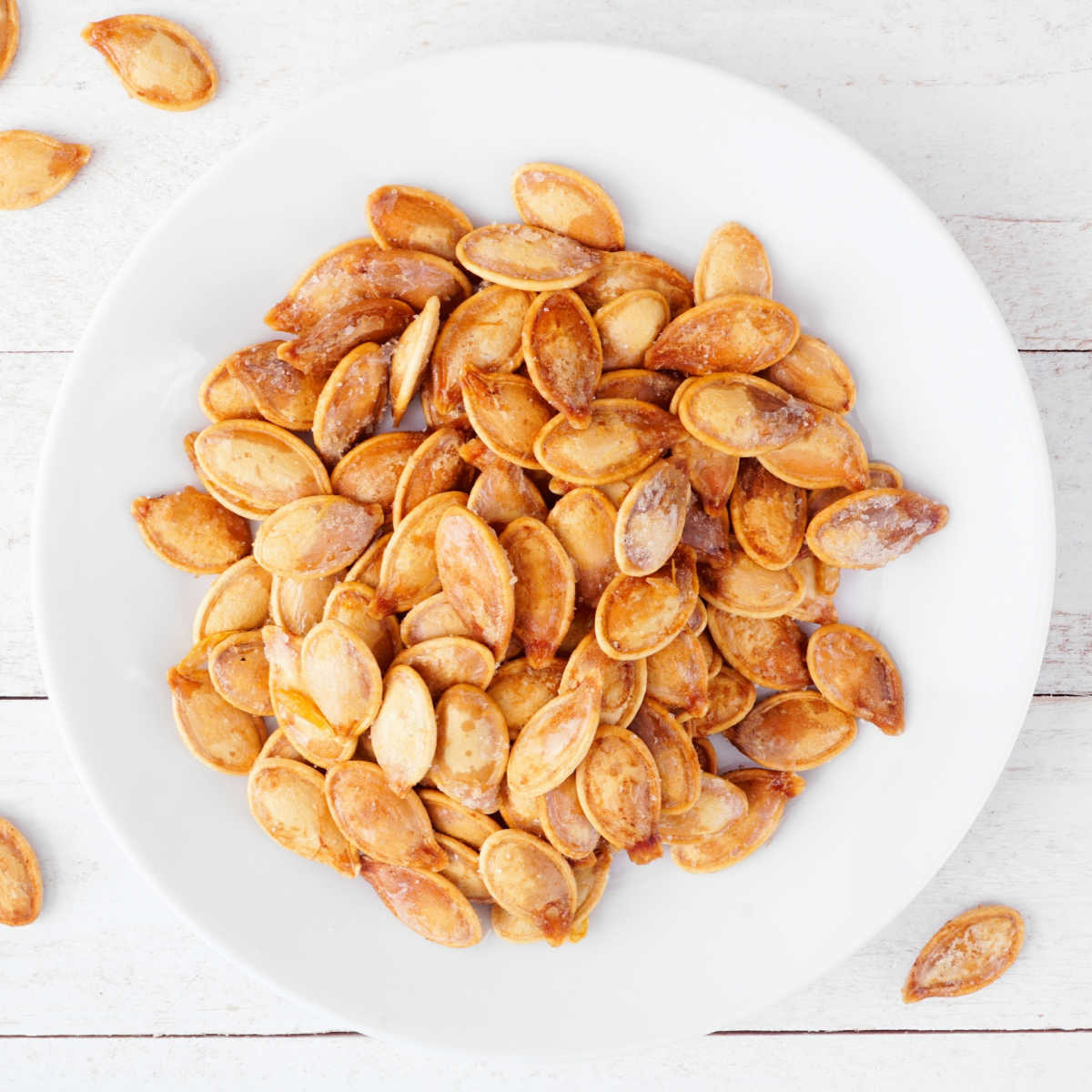 Roasted pumpkin seeds on a white plate.
