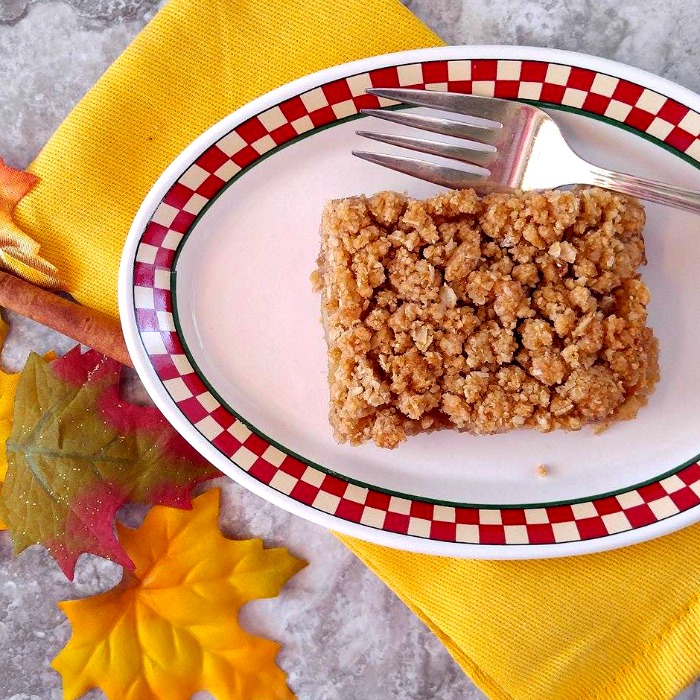 Apple Pie Bars on a red and white plate with fork, leaves and yellow napkin.