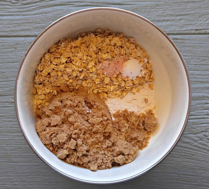 Brown sugar, flour, baking soda, salt and rolled oats in a bowl.
