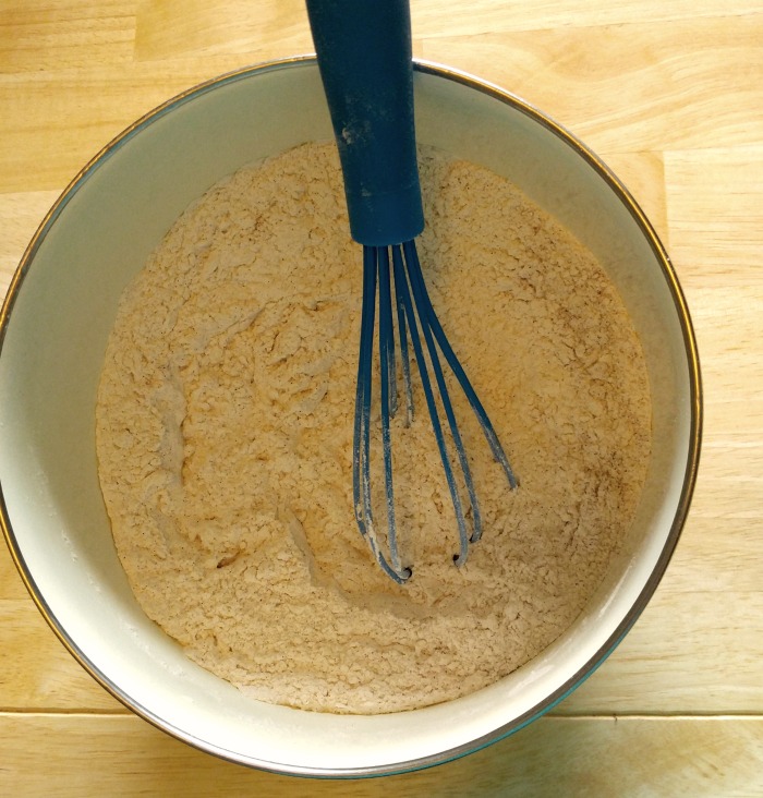 Dry ingredients fin a bowl with a blue whisk.