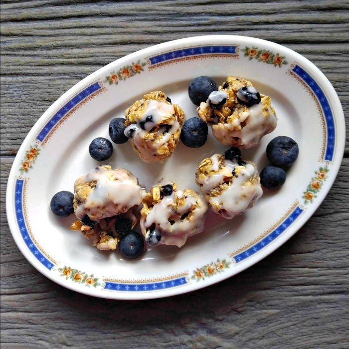 Blueberry granola bites on a white and blue plate with blueberries.