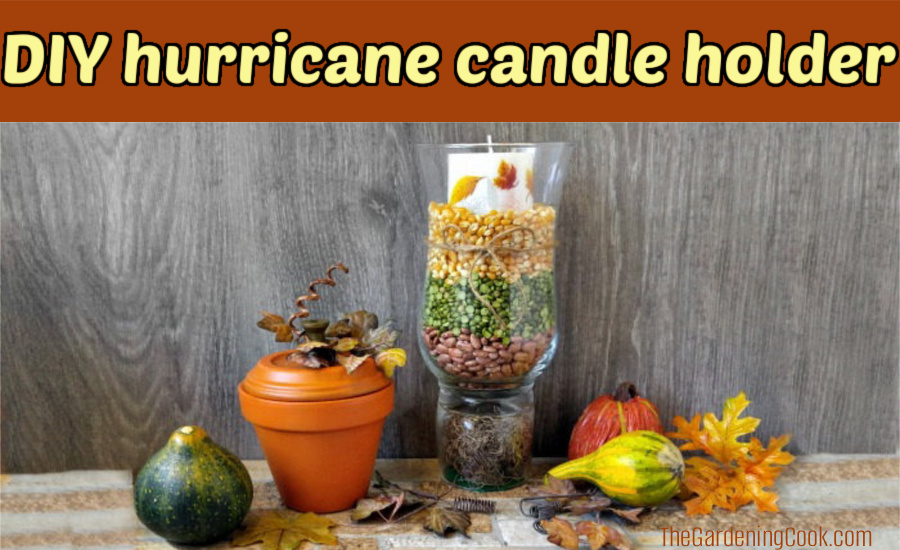 Popcorn, beans, seeds and moss surrounding a candle in a glass jar next to a clay pot pumpkin and fall gourds. Brown text box reads DIY hurricane candle holder.