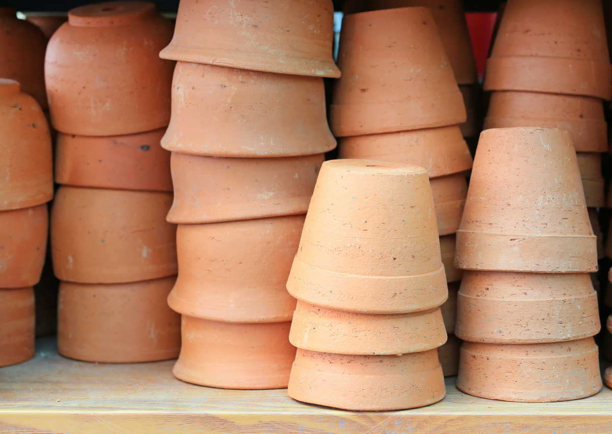 Clean clay pots in stacks sitting on a wooden shelf.