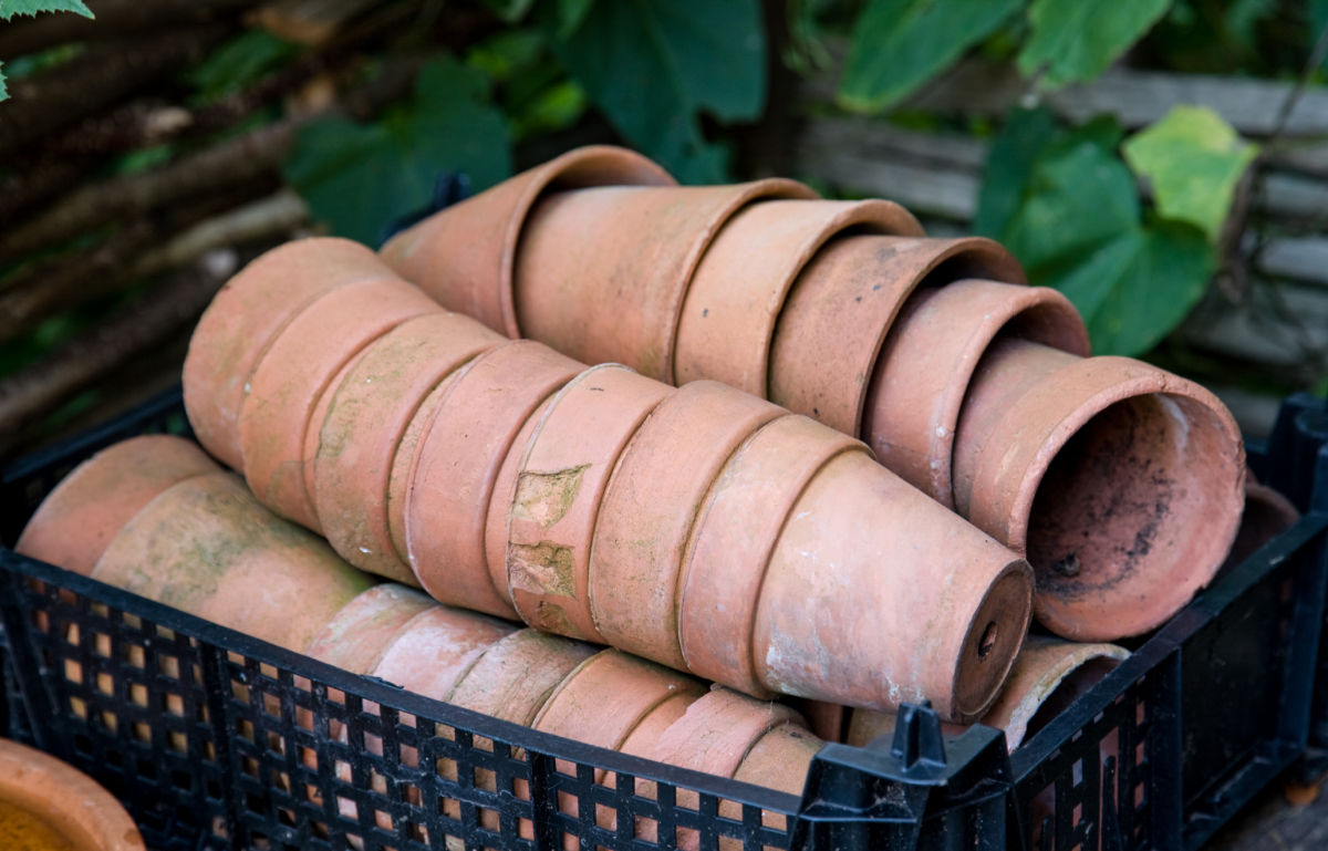 Piles of dirty terracotta pots in a black crate.