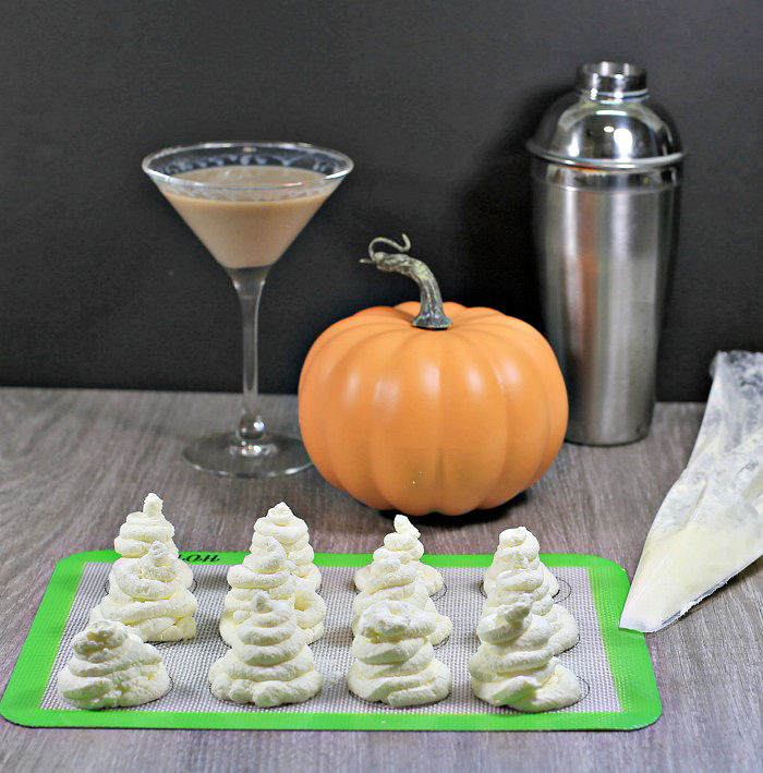 whipped cream ghosts on a silicone mat with pumpkin and cocktail tools.