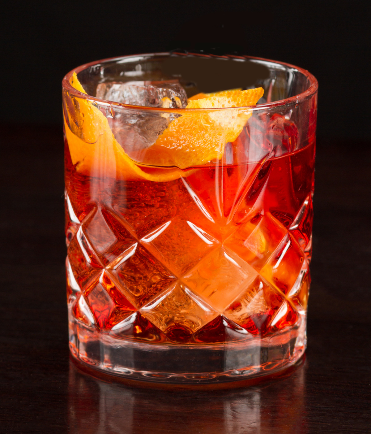 An orange drink in a rocks glass witih ice and orange peel.