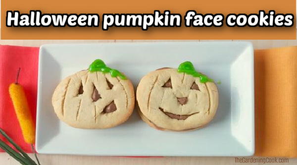 Two cookies shaped like Jack O Lanterns on a white plate next to an orange napkin.
