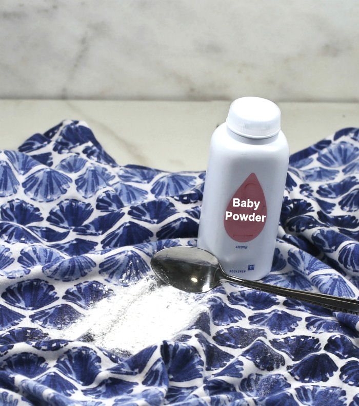Baby powder on an oil stain on blue shirt with spoon to scrape off.