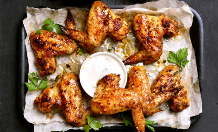 Oven baked chicken wings and white sauce.